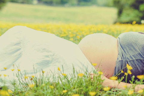 Pregnant woman lying in a field with yellow flowers